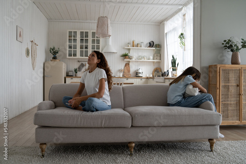 Teenager problems. Sad teenage daughter sitting separately on sofa ignoring mother, depressed teen girl hiding feelings emotions from parent, worried single mother Family conflict. Depression in teens