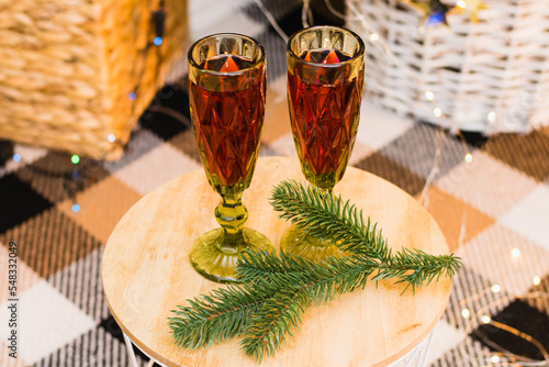 Concept of Christmas celebration and home comfort. Glasses with red wine on a table under a Christmas tree decorated with a garland and balls