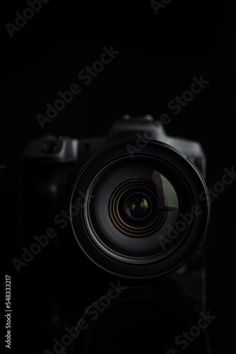 Digital mirrorless camera on black background. Lens closeup. Front view.