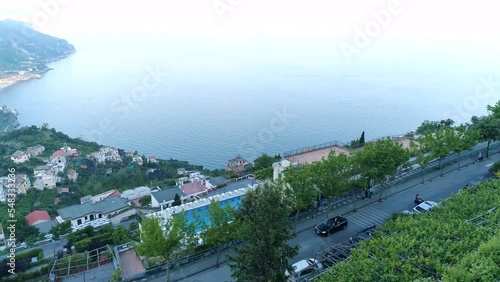 Aerial view of an Auto (Cabriolet) driving down a road on a cliff in Ravello, Italy. Drone flying smoothly over the  Amalfi Coast, Maiori and Tyrrhenian Sea.