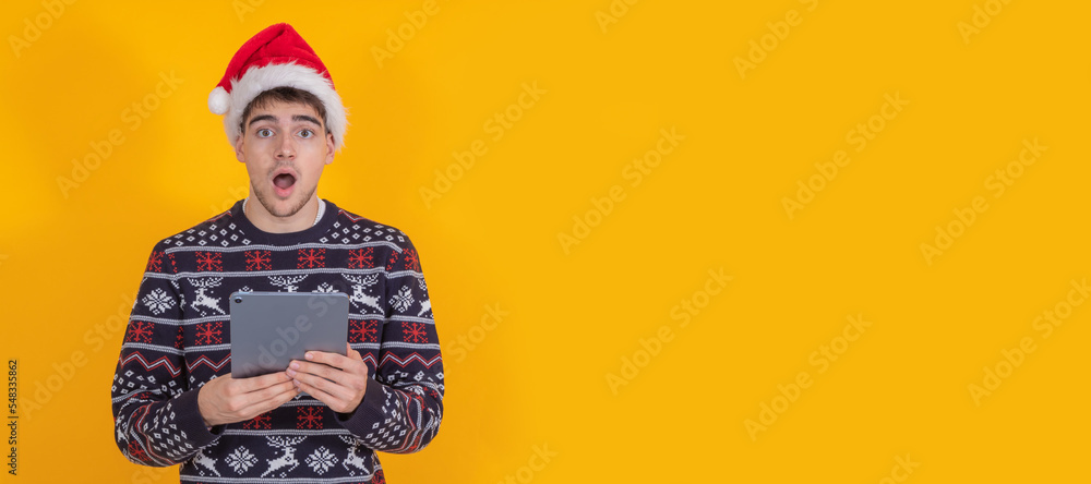 young santa claus isolated looking at tablet or laptop surprised young santa claus isolated looking at tablet or laptop surprised