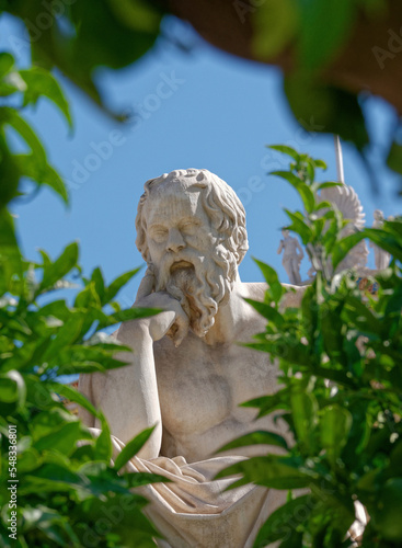 Socrates, the ancient Greek philosophers portrait, a detail of a marble statue seen through a lemon tree's foliage. Culture travel in Athens, Greece.