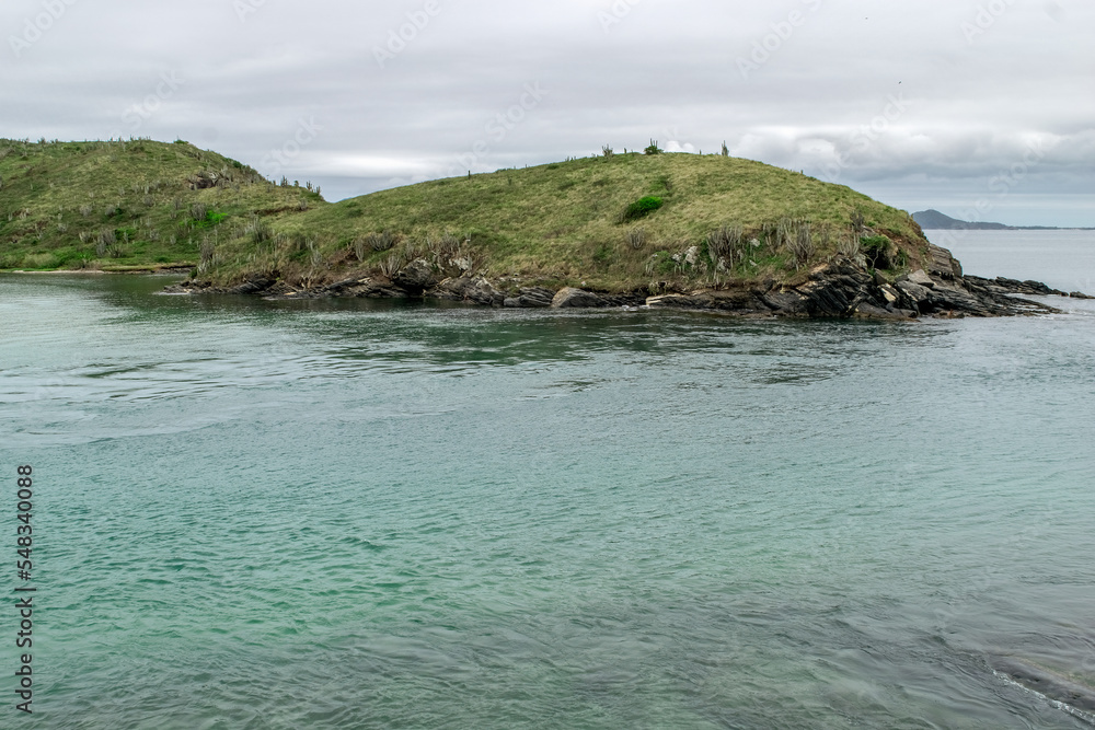 Fototapeta premium Praia no Forte São Mateus em Cabo Frio, com um lindo mar de águas verdes e muitas montanhas ao redor.