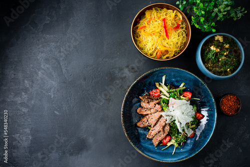 Asian food rice noodles with red pepper, homemade cheese with spinach, duck fillet salad.