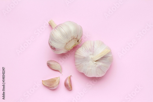 Fresh white unpeeled head bulb of garlic and garlic cloves on pink color background. Vegan, organic, vitamins. Natural antibiotic, antioxidant, Allicin. Top view. Flat lay
