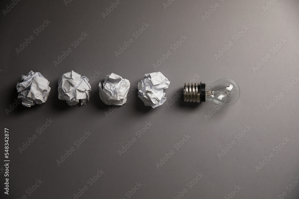 Crumpled papers and a light bulb. Concept discarded ideas Crumpled papers and a light bulb. Concept discarded ideas