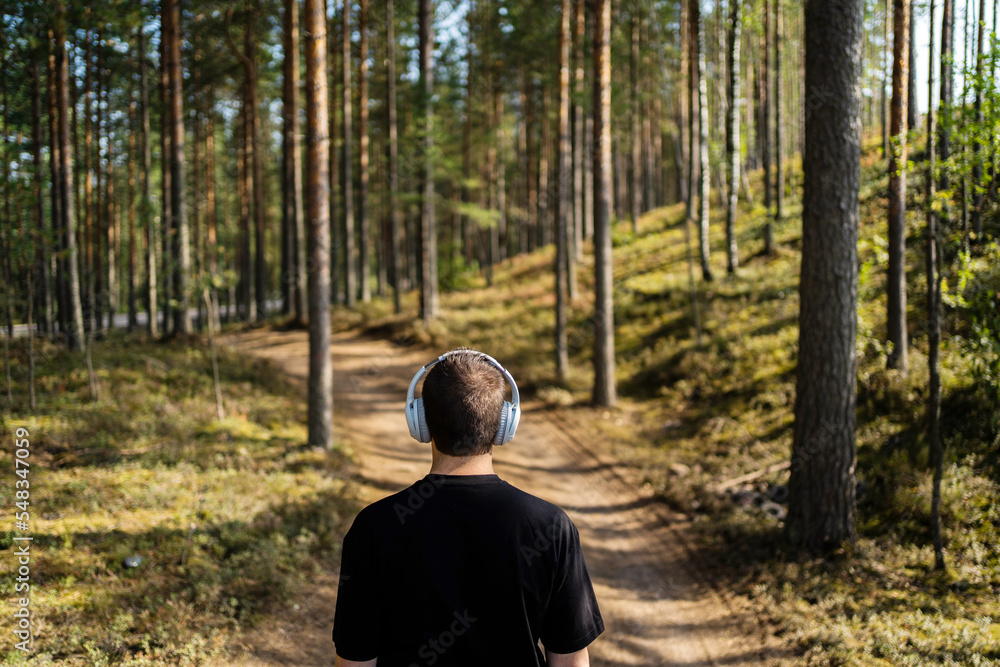 Listening to an audiobook with headphones and calm music in nature, a man looks at the horizon