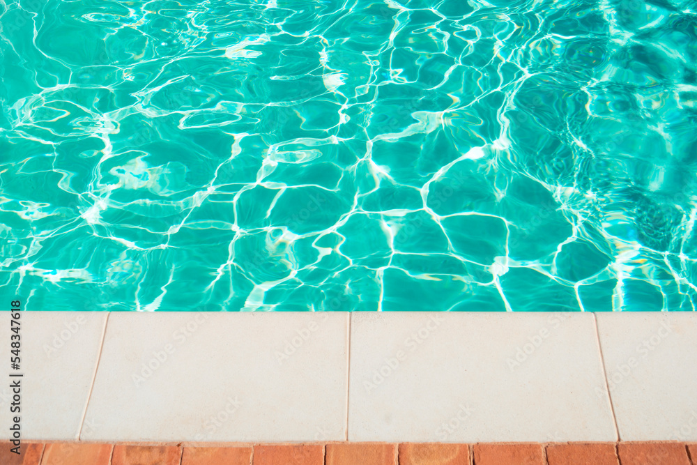 Obraz premium Swimming pool border. Close up edge of white cement floor near swimming pool with moving blue water.