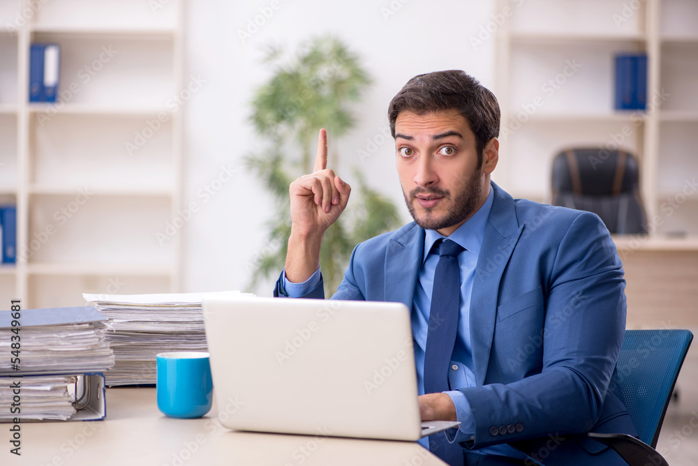 Young male employee and too much work in the office Young male employee and too much work in the office