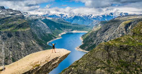 Amazing nature view with Trolltunga and a girl standing  on it. Location: Scandinavian Mountains, Norway, Stavanger. Artistic picture. Beauty world. The feeling of complete freedom