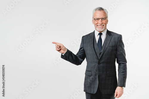 Successful rich confident caucasian mature middle-aged businessman in formal suit pointing showing copyspace freespace isolated in white background