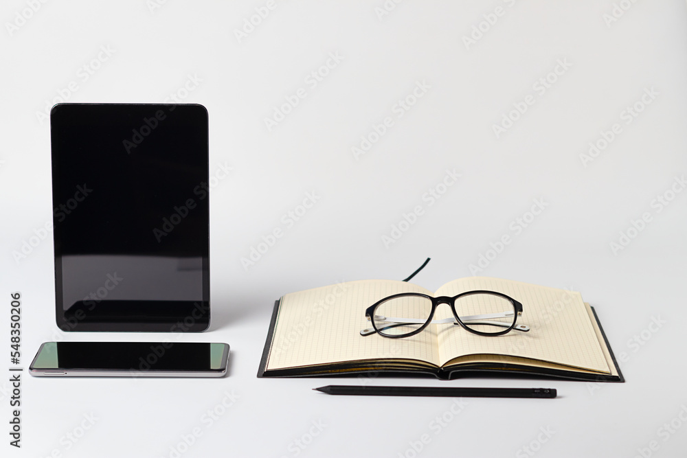 Eyeglasses, notebook with pencil, computer tablet and smartphone on white background, poor vision concept Eyeglasses, notebook with pencil, computer tablet and smartphone on white background, poor vision concept