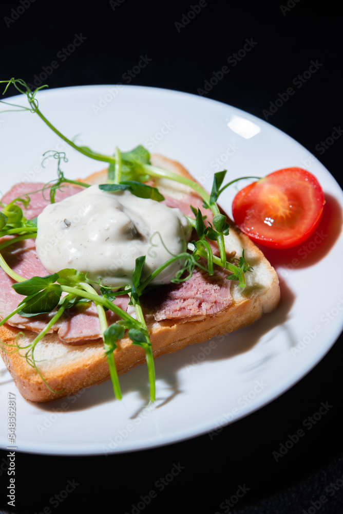sandwich with bacon and microgreens and tomatoes on a black background sandwich with bacon and microgreens and tomatoes on a black background