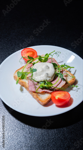 sandwich with bacon and microgreens and tomatoes on a black background