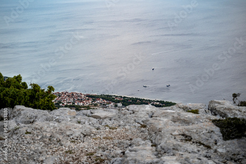 Town of Bol visible from the highest peak of Brac island, Croatia with boats passing along the shore