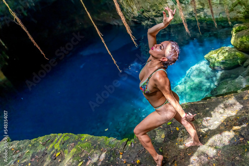 A Lovely Latin Model Enjoys The Beautiful Waters In The Cenotes Near Cuzama, Yucatan, Mexico photo