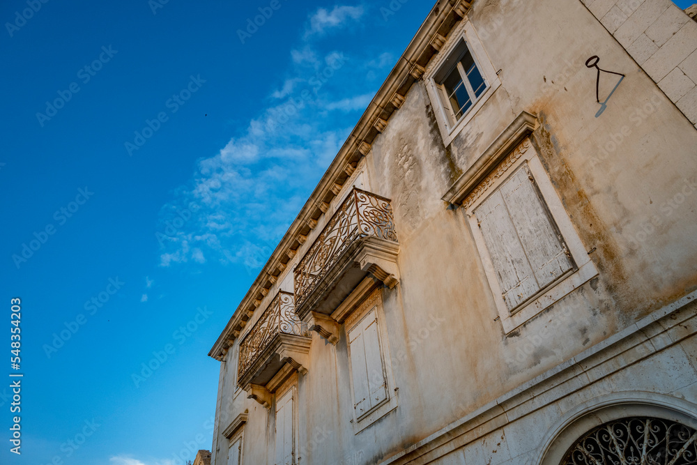 Beautiful old, stone house with iron fences on balconies, photographed against the clear, blue sky in the town of Milna on Brac island, Croatia