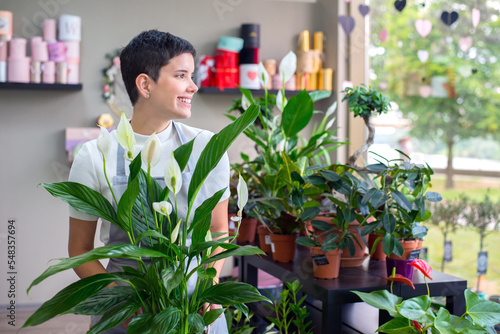 Young woman professional florist working with flowers in her flower shop in summer 