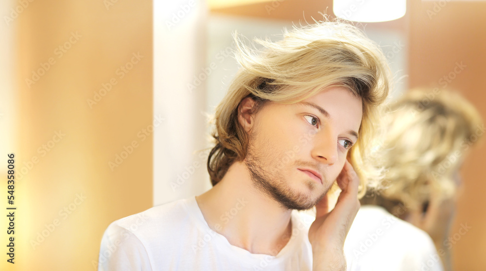 young man looking in the mirror,combing his hair,looking at problems on face. young man looking in the mirror,combing his hair,looking at problems on face.