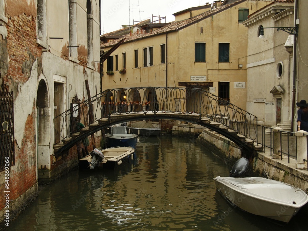 Bridge over a narrow canal sidelined by old buildings in Venice, Italy