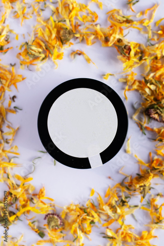 natural calendula cream with petals around it y white background