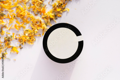 natural calendula cream with petals around it y white background