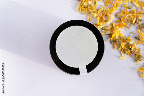 natural calendula cream with petals around it y white background