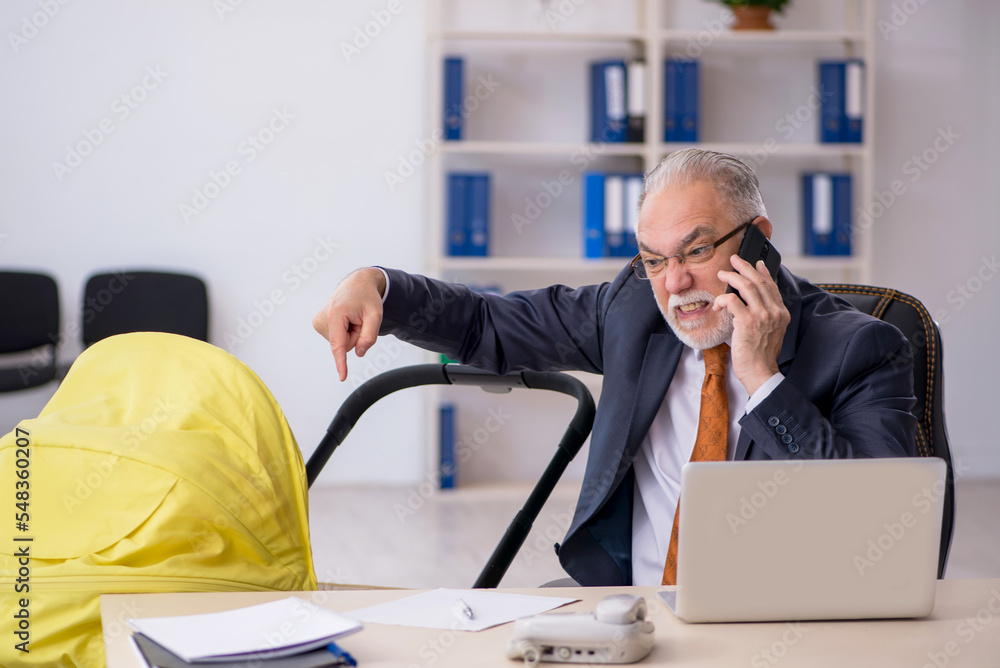 Old male employee looking after new born at workplace Old male employee looking after new born at workplace