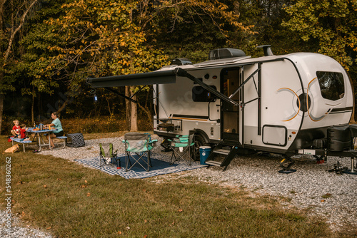 family camping with travel trailer camper and eating at picnic table © Jon