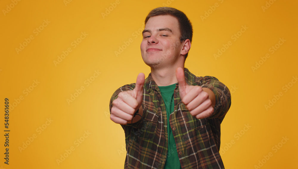 Like. Teenager adult man in green shirt raises thumbs up agrees with something or gives positive reply recommends advertisement likes good. Young guy boy isolated alone on yellow studio background Like. Teenager adult man in green shirt raises thumbs up agrees with something or gives positive reply recommends advertisement likes good. Young guy boy isolated alone on yellow studio background