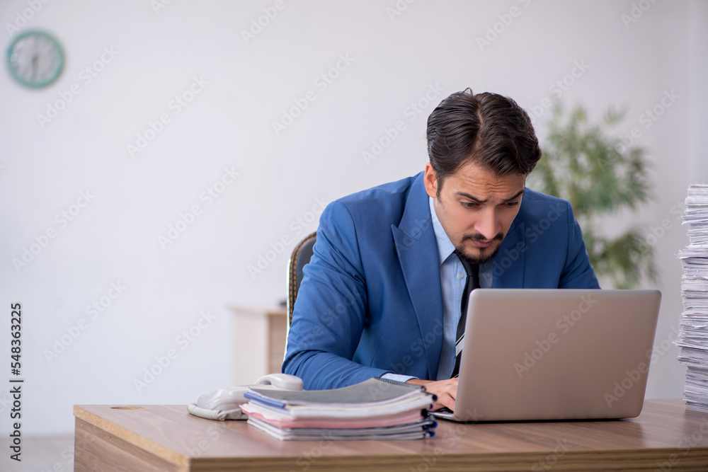 Young male employee unhappy with excessive work in the office Young male employee unhappy with excessive work in the office