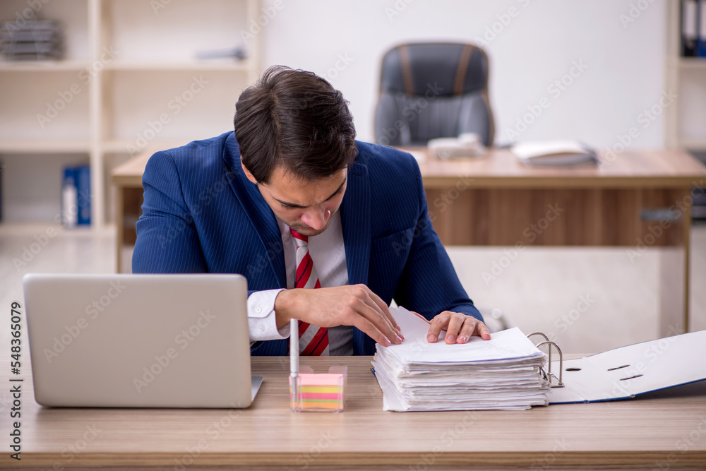 Young male employee and too much work in the office Young male employee and too much work in the office