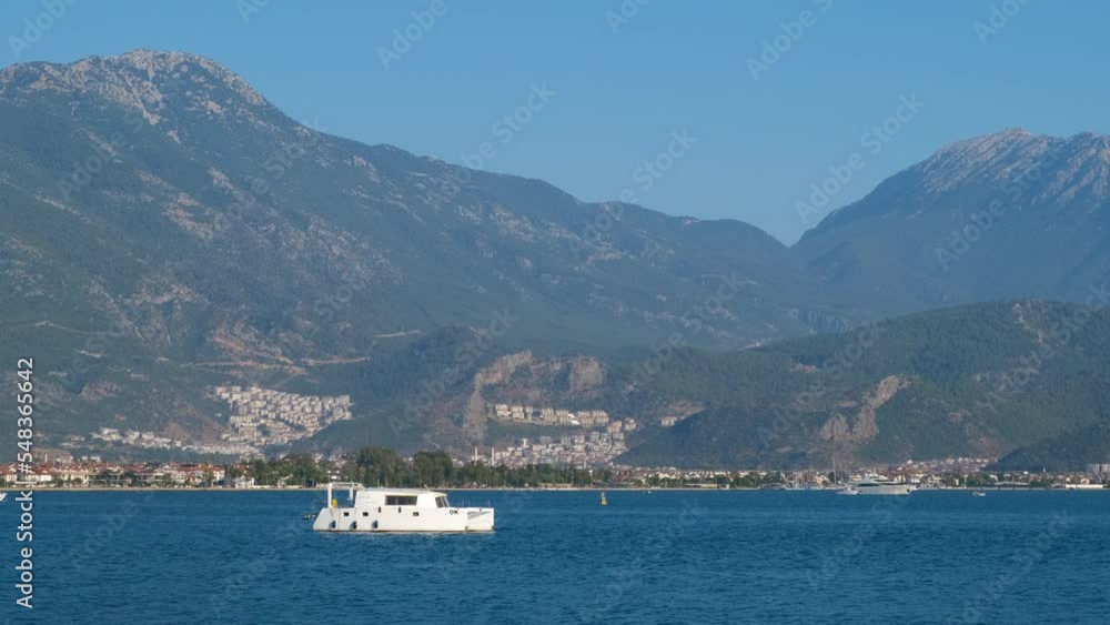 Yacht at anchor. A small yacht stands in the sea bay against the backdrop of mountains.