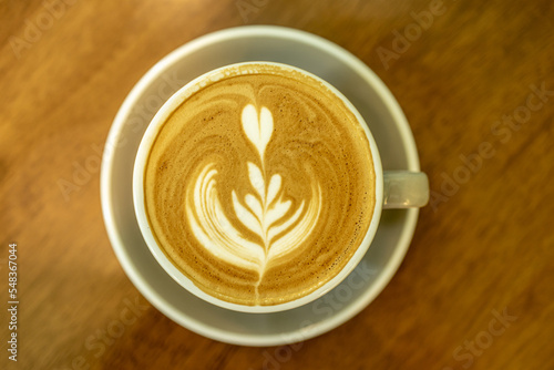 Close up, Latte coffee with heart shaped art in cup on a wood table background. Cup of coffee with beautiful latte art on wooden table and space for text, coffee time concept, beautiful latte art.