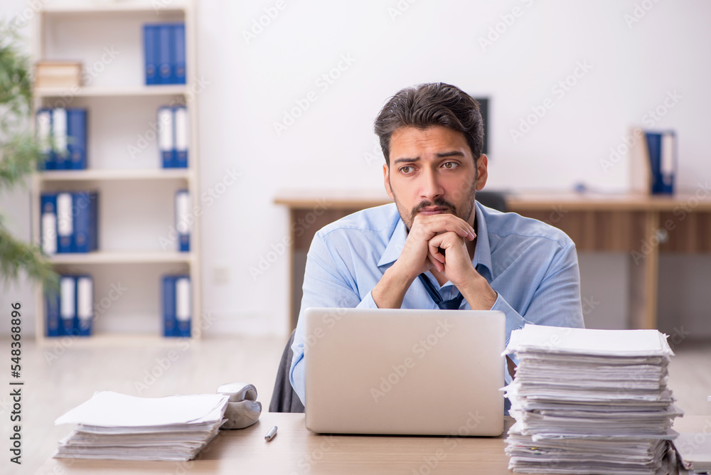 Young male employee and too much work in the office Young male employee and too much work in the office