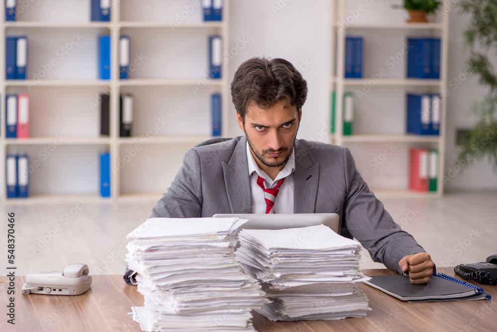 Young male employee unhappy with excessive work in the office