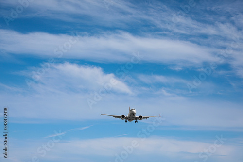 Modern white airplane flying in cloudy sky