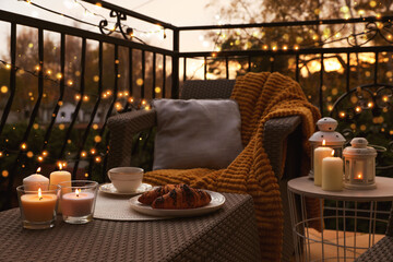 Beautiful view of garden furniture with pillow, soft blanket and burning candles at balcony