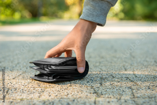 Man picking lost wallet from ground outdoors, closeup. Space for text