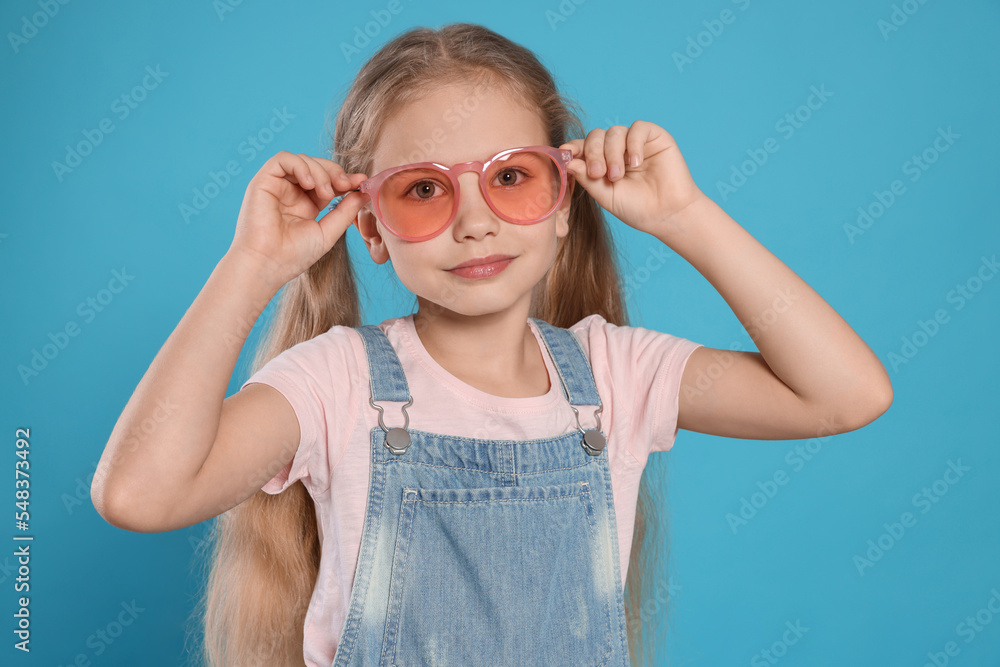 Girl in pink sunglasses on light blue background