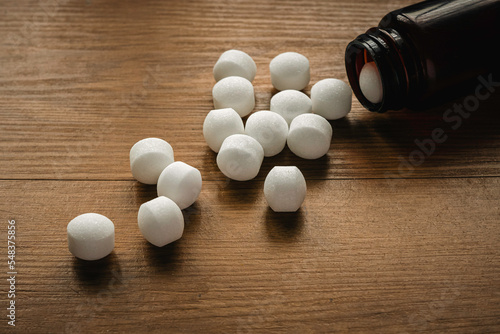 Naphthalene mothballs on wooden background.