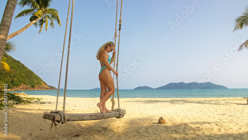 Seductive woman swinging on a swing on a tropical beach, on shores of the turquoise sea. Concept travel, walks, rest in sea, tropical resort coastline relaxation traveling tourism summer holidays