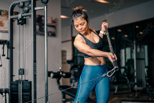 Asian woman working out in gym doing exercise focusing on the muscles arms and shoulders.Fitness, healthy style concept