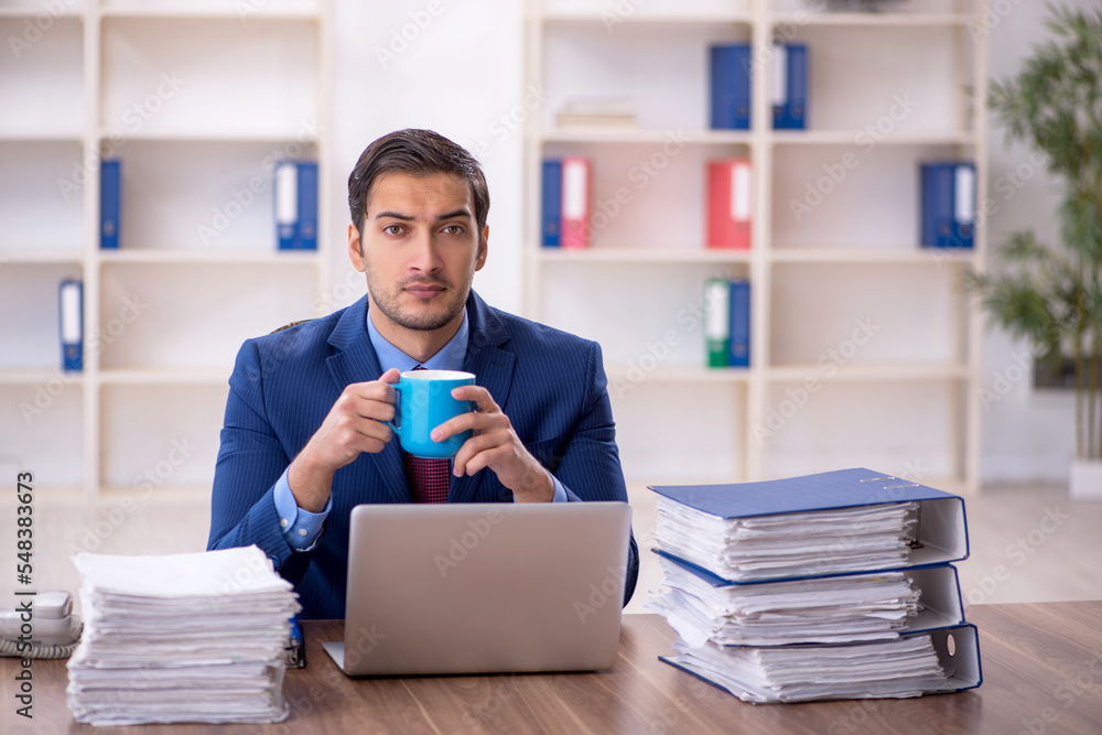 Young male employee and too much work in the office Young male employee and too much work in the office