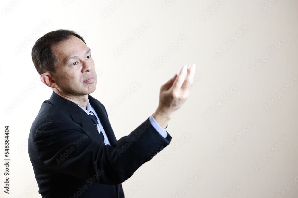 Middle-aged Japanese male businessman wearing navy blue suit on white background. Conceptual image of a project proposal, strategic business success and negotiation closing. Middle-aged Japanese male businessman wearing navy blue suit on white background. Conceptual image of a project proposal, strategic business success and negotiation closing.