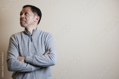 Middle-aged Japanese man in gray turtleneck wool sweater under white background. Concept image of Warm Biz, stability in daily life, and sustainable living. © DRN Studio