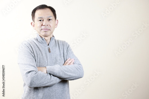 Middle-aged Japanese man in gray turtleneck wool sweater under white background. Concept image of Warm Biz, stability in daily life, and sustainable living.