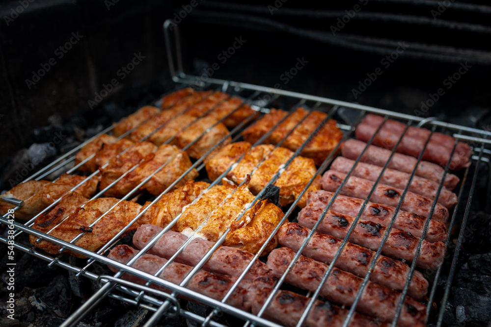 Meat and sausages on the grill are prepared for roasting on a picnic.