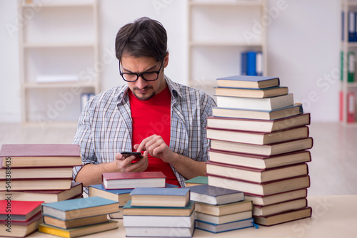 Young male student and too many books in the classroom