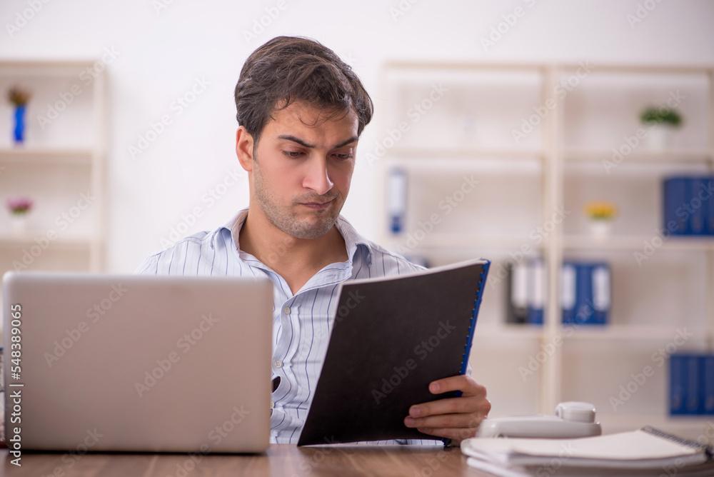 Young male employee and too much work in the office Young male employee and too much work in the office